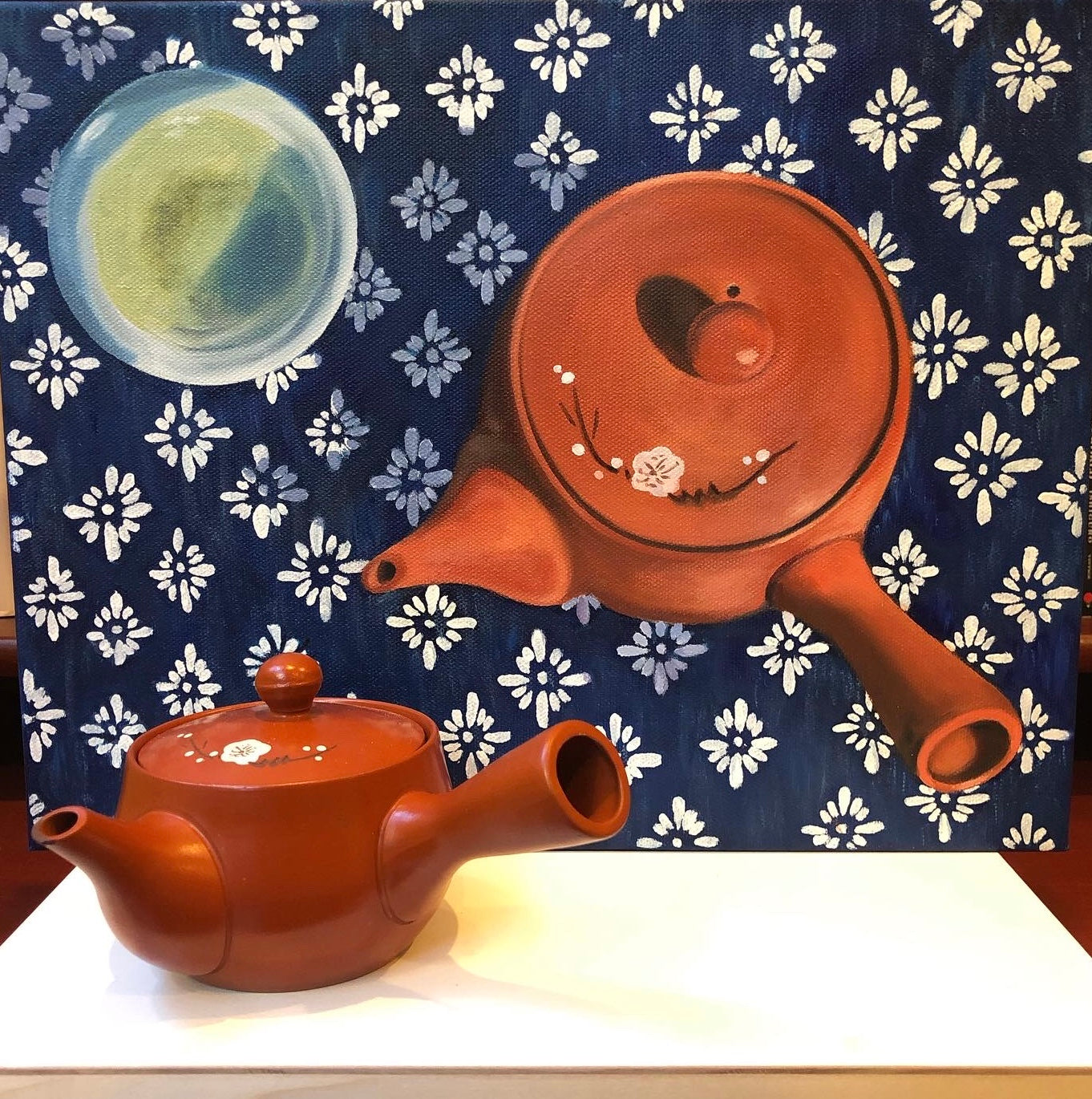 still life oil painting of traditional terra cotta Japanese teapot and cup of green tea on an indigo shibori tablecloth in front of teapot